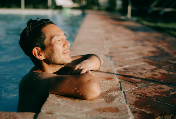 Man in the sun on the edge of the pool