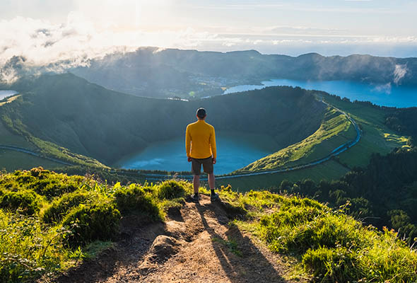 Person standing on mountain looking at valley below