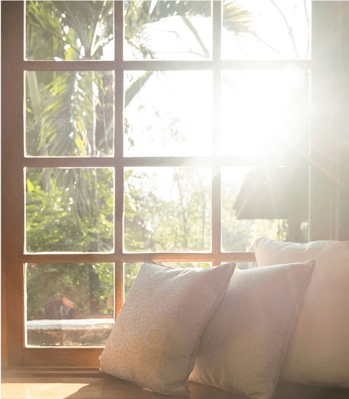 A cozy window seat in a house with pillows.