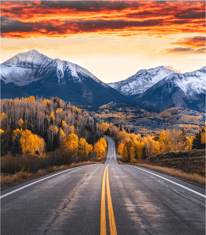 A long road leading towards beautiful snowcapped mountains.